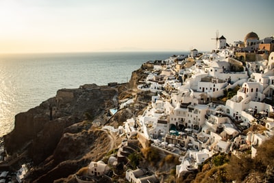 white concrete houses on brown rock formation near body of water during daytime